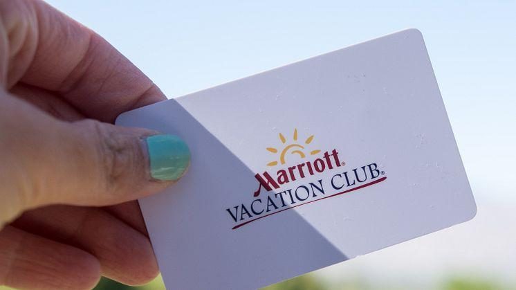 Hand holding a Marriott Vacation Club membership card against a bright blue sky background