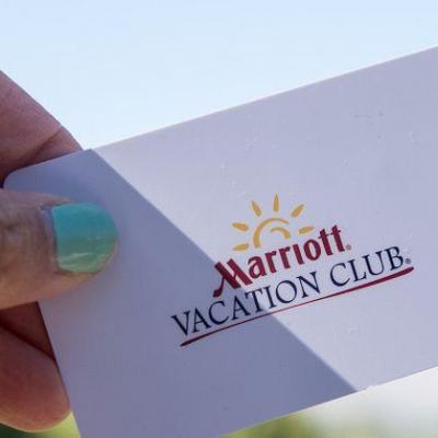 Hand holding a Marriott Vacation Club membership card against a bright blue sky background